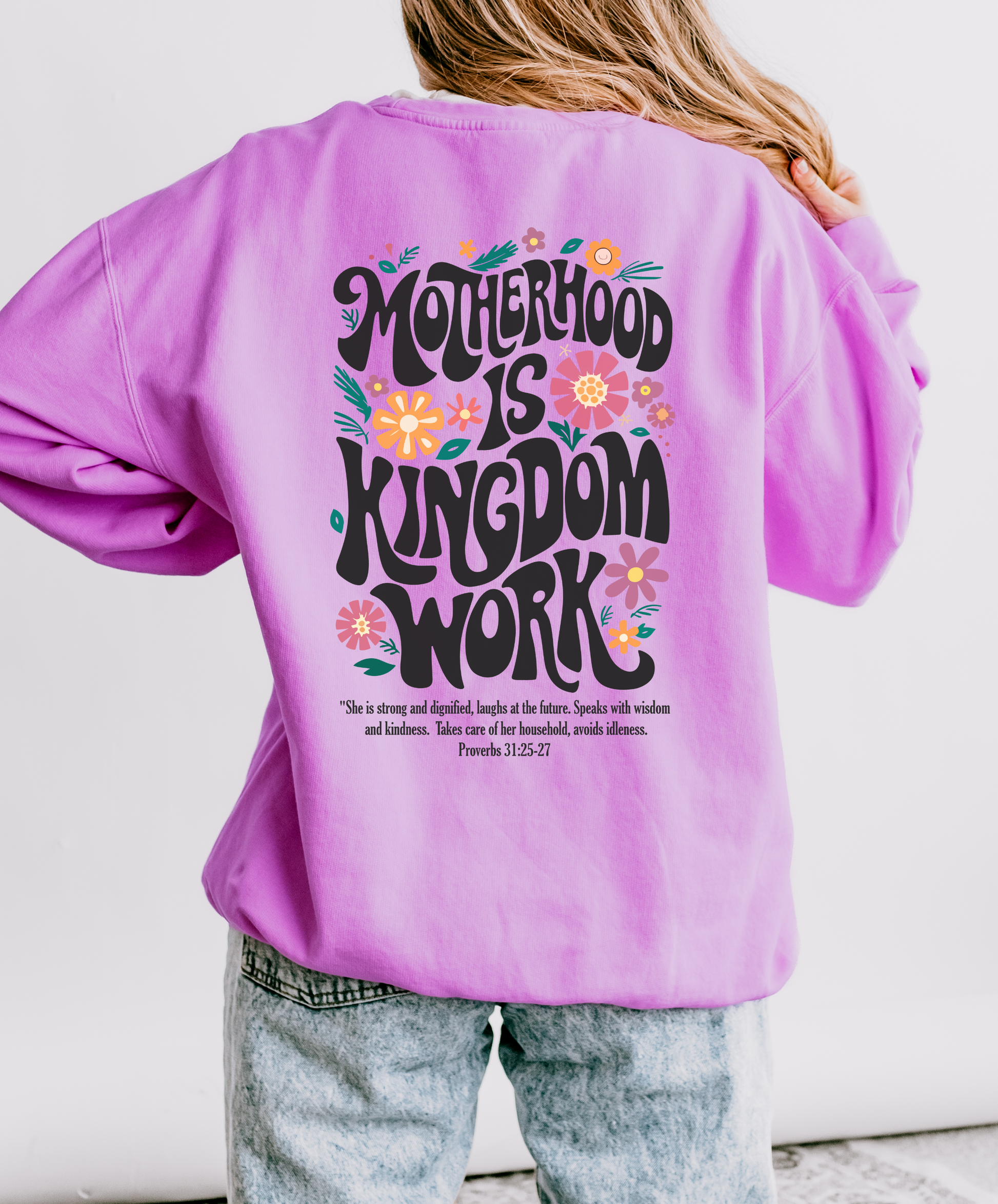 Person wearing a purple sweatshirt with 'Motherhood is Kingdom Work' text on the back.
