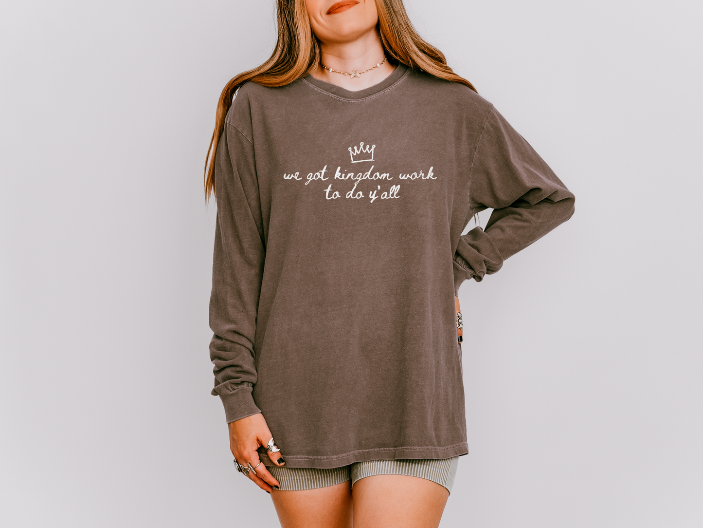 Person wearing a brown long-sleeve shirt with text on a plain background