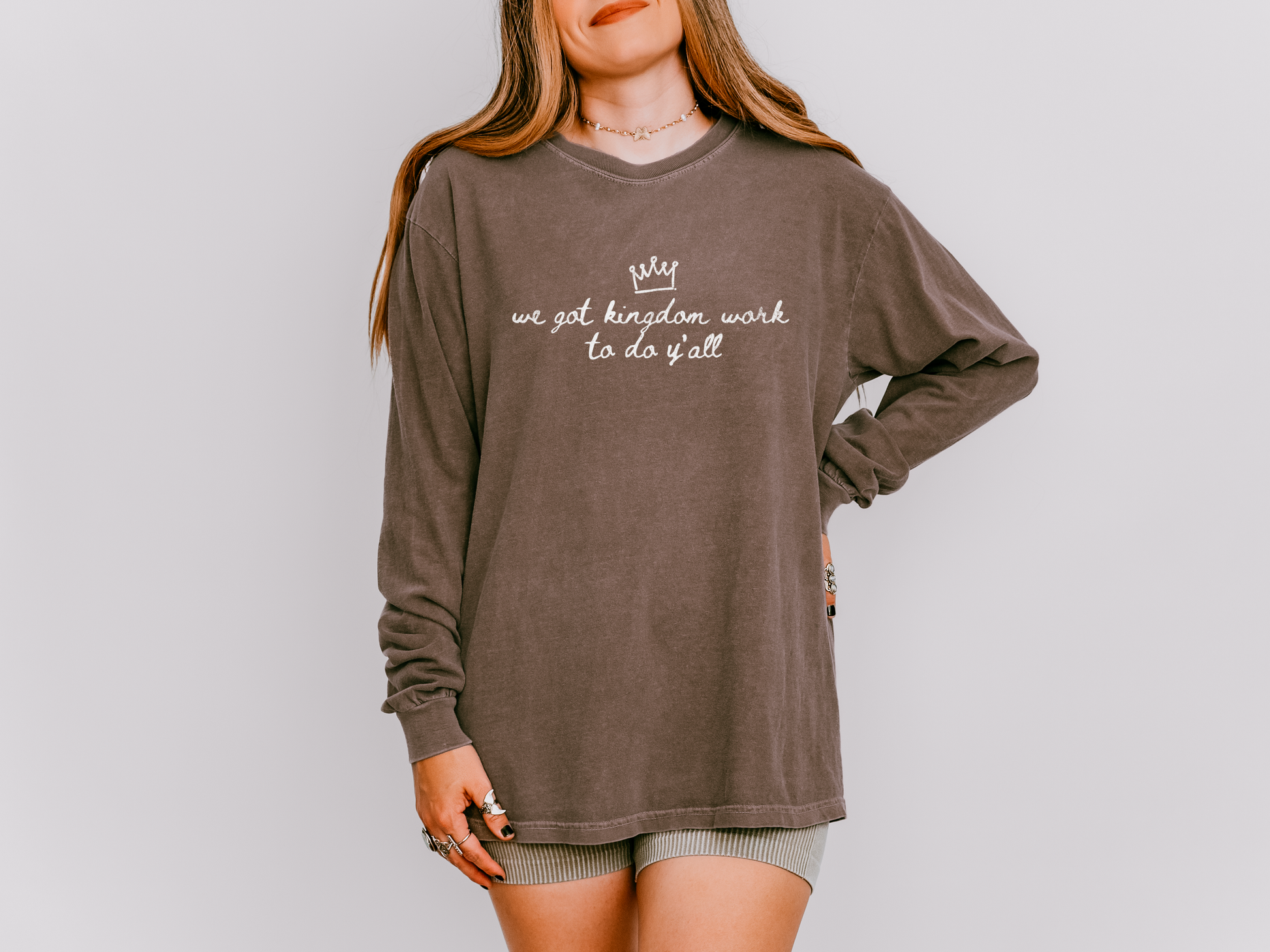 Person wearing a brown long-sleeve shirt with text on a plain background