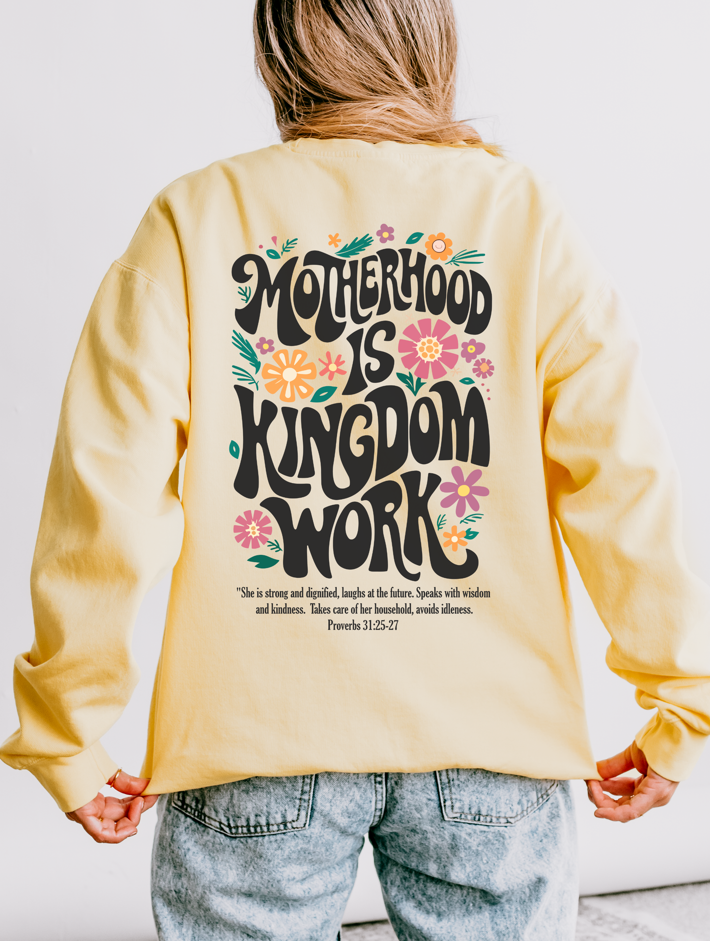 Person wearing a yellow sweatshirt with 'Motherhood is Kingdom Work' text on the back.